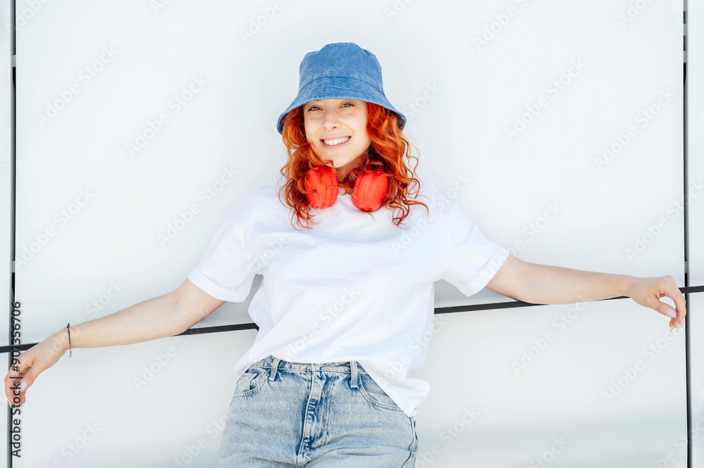 Smiling woman wearing bucket hat leaning on white wall Smiling woman wearing bucket hat leaning on white wall