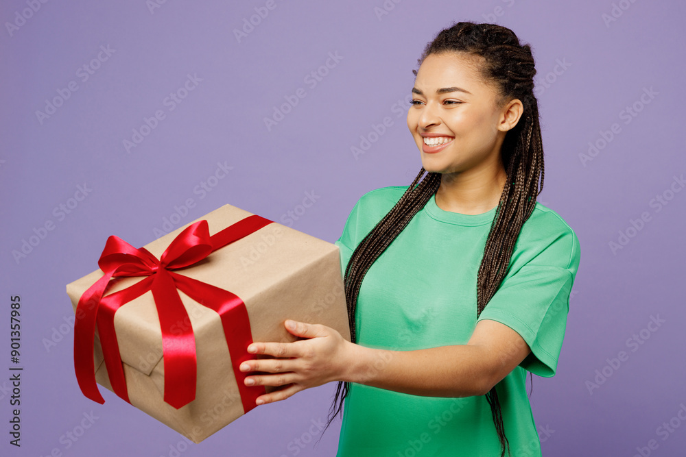 Young fun woman of African American ethnicity with dreadlocks wear green t-shirt casual clothes hold give present box with gift ribbon bow isolated on plain light purple background. Lifestyle concept. Young fun woman of African American ethnicity with dreadlocks wear green t-shirt casual clothes hold give present box with gift ribbon bow isolated on plain light purple background. Lifestyle concept.