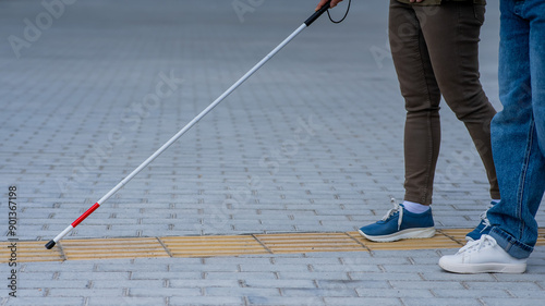 Close-up of a woman's legs accompanying a blind elderly lady outdoors. photo