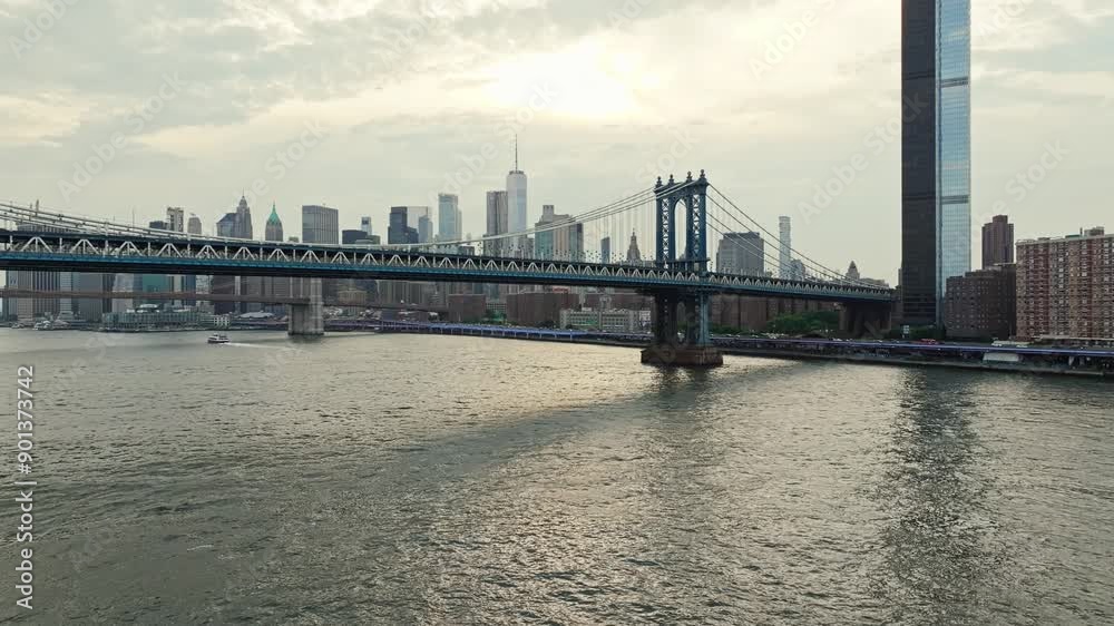 Drone rises to establish Manhattan bridge with NYC skyline in distance, city establishing shot at midday Drone rises to establish Manhattan bridge with NYC skyline in distance, city establishing shot at midday