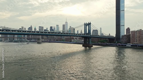 Drone rises to establish Manhattan bridge with NYC skyline in distance, city establishing shot at midday photo
