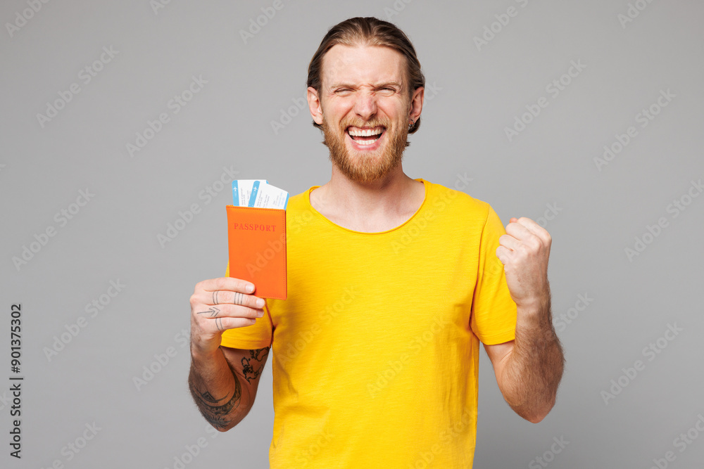 Traveler man wear yellow casual clothes hold passport ticket do winner gesture isolated on plain grey background. Tourist travel abroad in free spare time rest getaway Air flight trip journey concept Traveler man wear yellow casual clothes hold passport ticket do winner gesture isolated on plain grey background. Tourist travel abroad in free spare time rest getaway Air flight trip journey concept