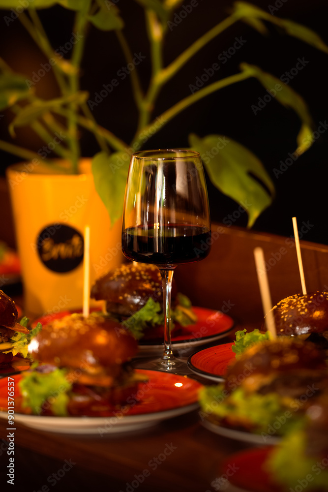 A glass of red wine with delicious dishes, special Angus burger with arugula and dry wine. A glass of red wine with delicious dishes, special Angus burger with arugula and dry wine.