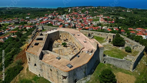 Chlemoutsi castle museum surrounded by a village and lush green landscape, aerial view