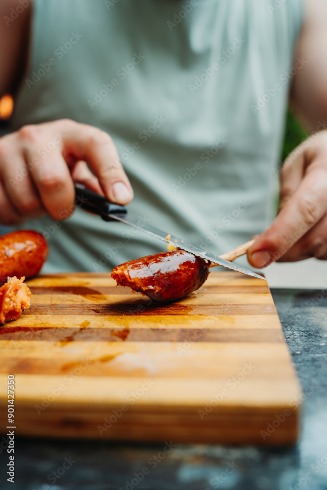 Close up of man hands cutting bbq sausage with knife Close up of man hands cutting bbq sausage with knife