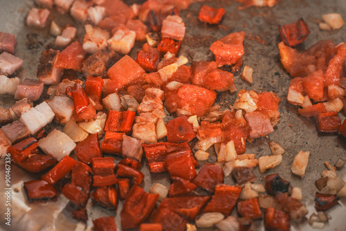 Tomatoes, paprika, shallots and bacon are fried in a steel pan. photo