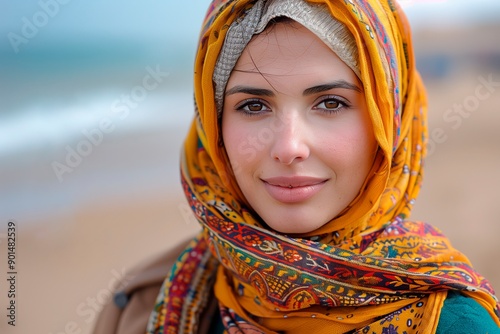 Young woman wearing colorful scarf smiling on sandy beach during a sunny day, copyspace for text photo