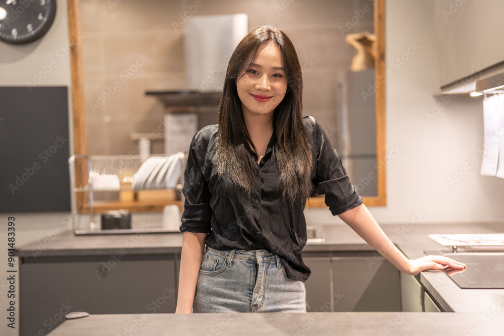 Portrait of asian young woman smiling confidently with a welcoming gesture in a modern kitchen on kitchen background features cooking utensils, cooking, kitchen activities and food preparation Portrait of asian young woman smiling confidently with a welcoming gesture in a modern kitchen on kitchen background features cooking utensils, cooking, kitchen activities and food preparation