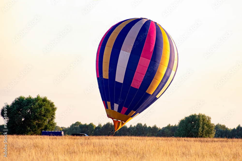 Obraz premium A colorful hot air balloon takes off for a flight at sunrise in the field. Concept of travel and outdoor activities.
