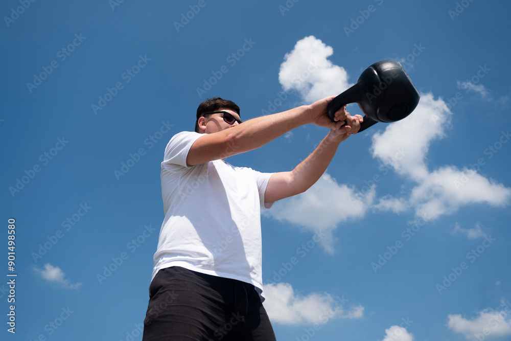 Sportive man workout with kettlebell outdoor in spring or summer Sportive man workout with kettlebell outdoor in spring or summer