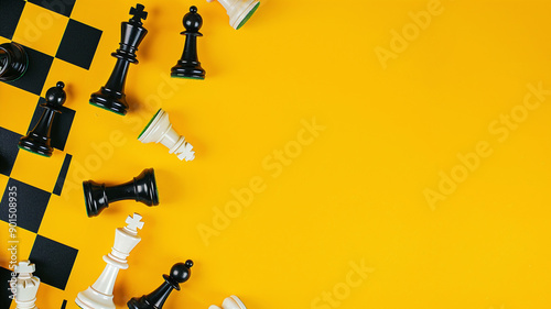 Fototapeta Naklejka Na Ścianę i Meble -  Chess pieces black and white on a yellow background with a chessboard with space for text. Design frame for text, business advertising and international chess day