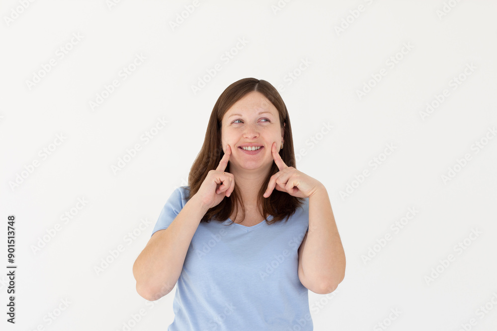 Young brunette woman pointing fingers at her cheeks isolated over white background Young brunette woman pointing fingers at her cheeks isolated over white background