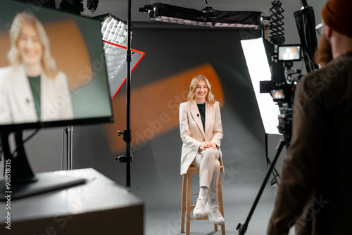 Woman in casual outfit sitting in professional video recording studio with camera and lights