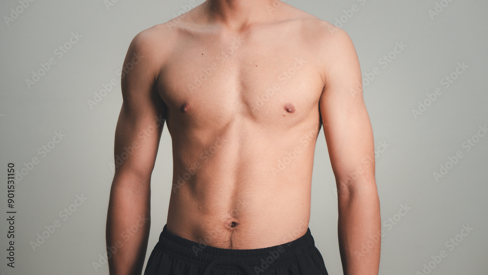 Handsome muscular young man posing against a grey background. male model taking off his shirt on a gray background, body transformation , weight loss, sixpack Handsome muscular young man posing against a grey background. male model taking off his shirt on a gray background, body transformation , weight loss, sixpack