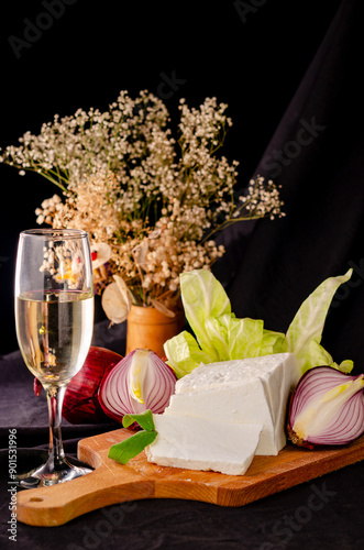 still life with cheese, onion and a glass of white wine on a black background photo