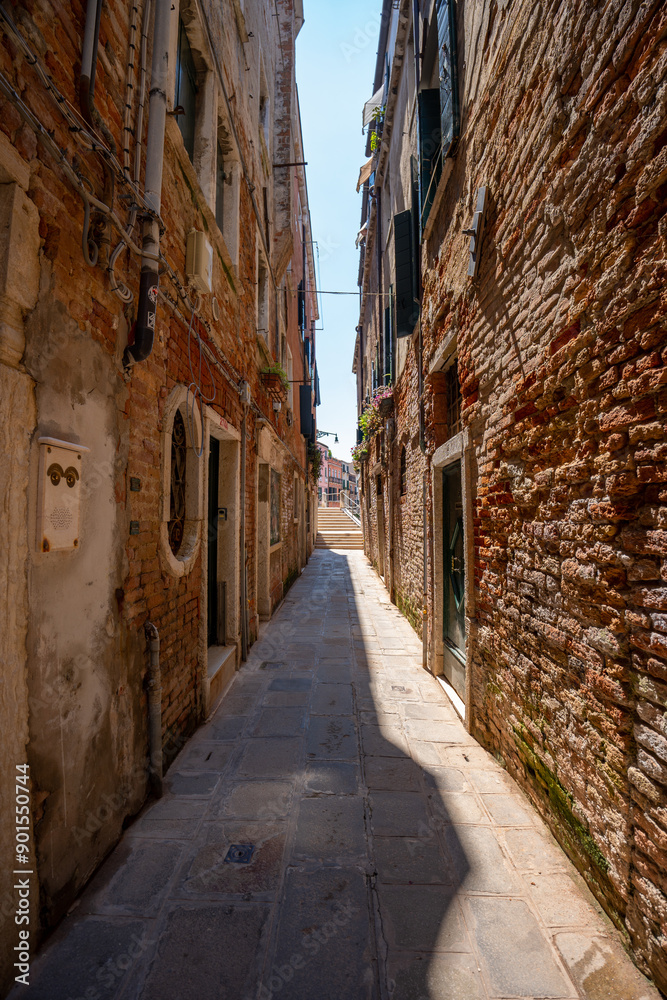 Venice, Italy - June 05, 2024: Narrow empty street framed with brick buildings. Venice, Italy - June 05, 2024: Narrow empty street framed with brick buildings.