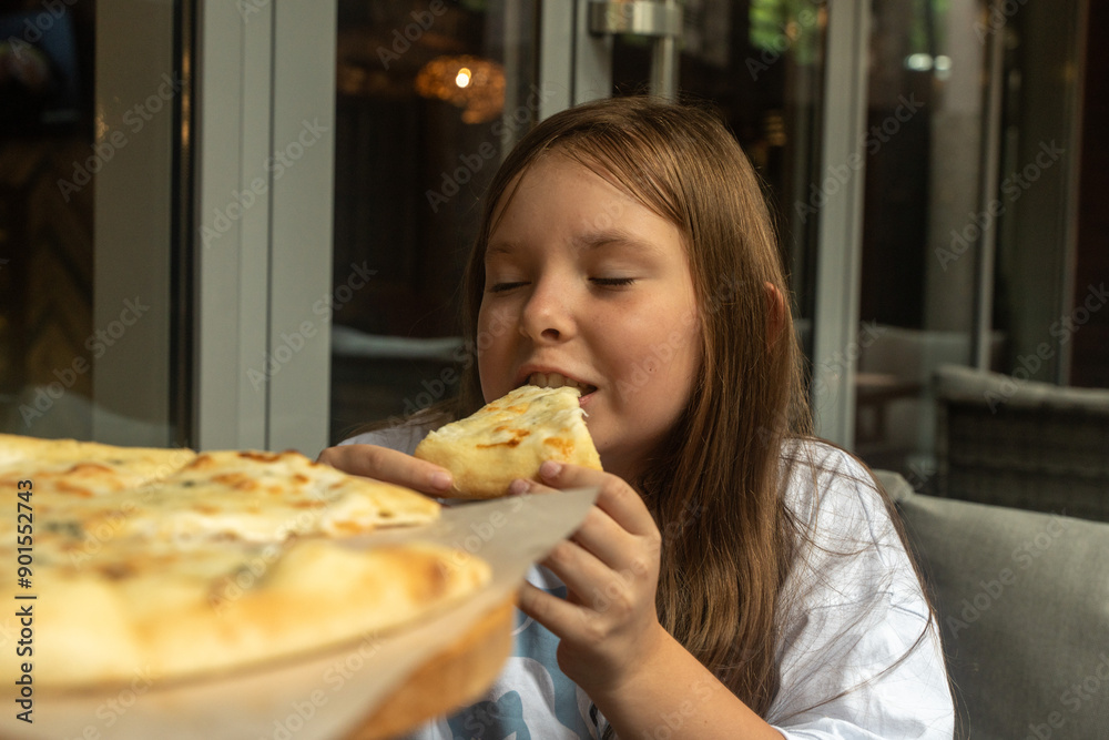 Little pre-teen girl eating cheese pizza while enjoying the taste with her eyes closed. Children's favorite food Little pre-teen girl eating cheese pizza while enjoying the taste with her eyes closed. Children's favorite food