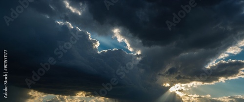 Dramatic sky with rays of light piercing through dark clouds evoking a sense of awe and the sublime beauty of nature.