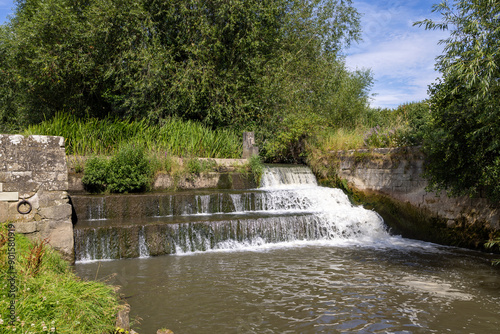 Photo of the beautiful town of Bedale, which is a market town and civil parish in North Yorkshire, England showing the Bedale Beck and waterfall on a hot sunny day in the summer time photo