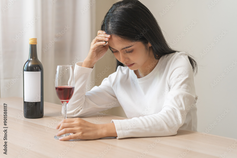 Alcoholism drunk asian young woman hand holding glass of red wine with whiskey bottle, female sitting alone, drinking on table at home. Treatment of alcohol addiction, suffer abuse problem alcoholism Alcoholism drunk asian young woman hand holding glass of red wine with whiskey bottle, female sitting alone, drinking on table at home. Treatment of alcohol addiction, suffer abuse problem alcoholism