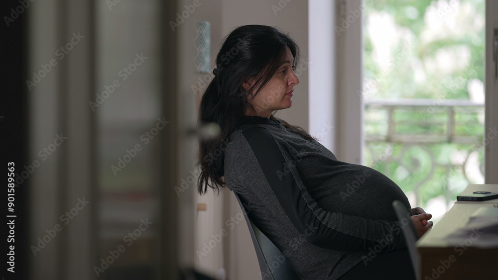 Pregnant woman sitting at a desk, side view, thoughtful expression, indoor setting, natural light from window, expecting mother, contemplation, peaceful moment, home environment Pregnant woman sitting at a desk, side view, thoughtful expression, indoor setting, natural light from window, expecting mother, contemplation, peaceful moment, home environment