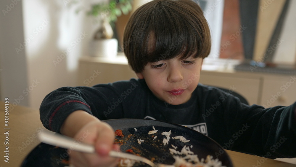 Young boy eating rice with tomato sauce, holding a fork and eagerly taking a bite, showcasing a candid moment of childhood mealtime and enjoyment, ideal for lifestyle Young boy eating rice with tomato sauce, holding a fork and eagerly taking a bite, showcasing a candid moment of childhood mealtime and enjoyment, ideal for lifestyle