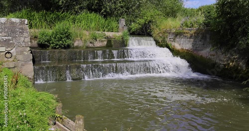 Slow motion footage of the beautiful town of Bedale, which is a market town and civil parish in North Yorkshire, England showing the Bedale Beck and waterfall on a hot sunny day in the summer time photo