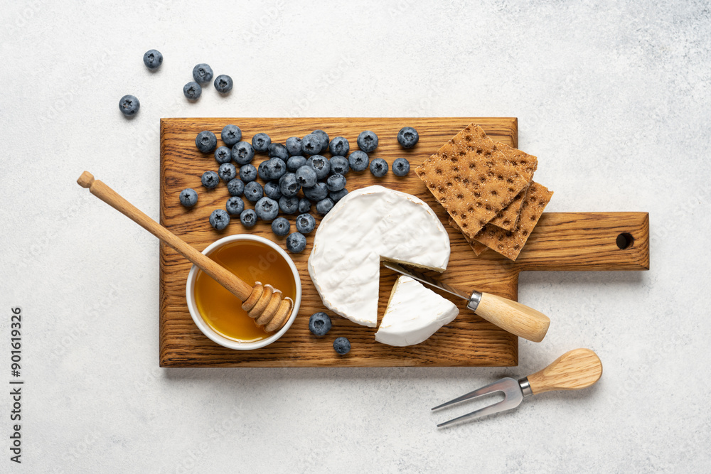 Soft Camembert cheese on wooden board with honey and blueberries. Cheese platter on white background Soft Camembert cheese on wooden board with honey and blueberries. Cheese platter on white background