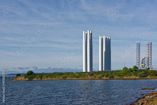 Wind Turbine Towers upright and waiting for onward transportation at the Port of Dundee, with a Jack Up oil Rig in the background.