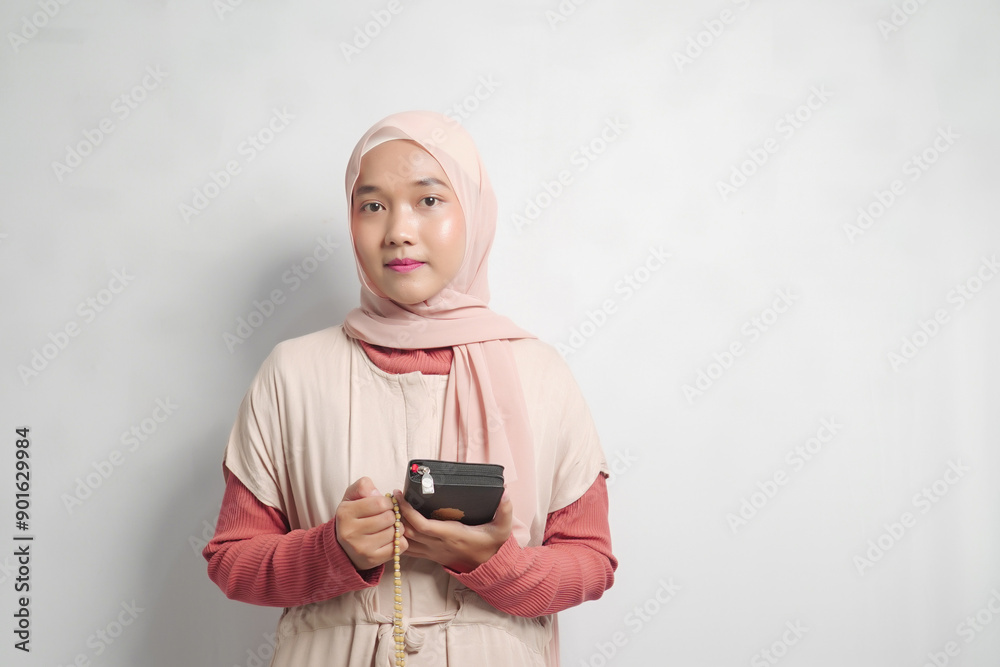 Young woman in hijab holding a Quran and prayer beads Young woman in hijab holding a Quran and prayer beads