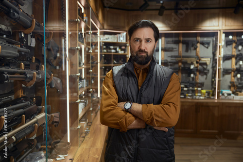 Pensive man choosing rifle gun looking at showcase in store