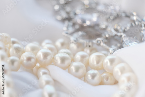 Close-up of a pearl necklace with a sparkling diamond pendant on a white fabric background. This image captures the elegance and luxury of fine jewelry, showcasing the exquisite craftsmanship and