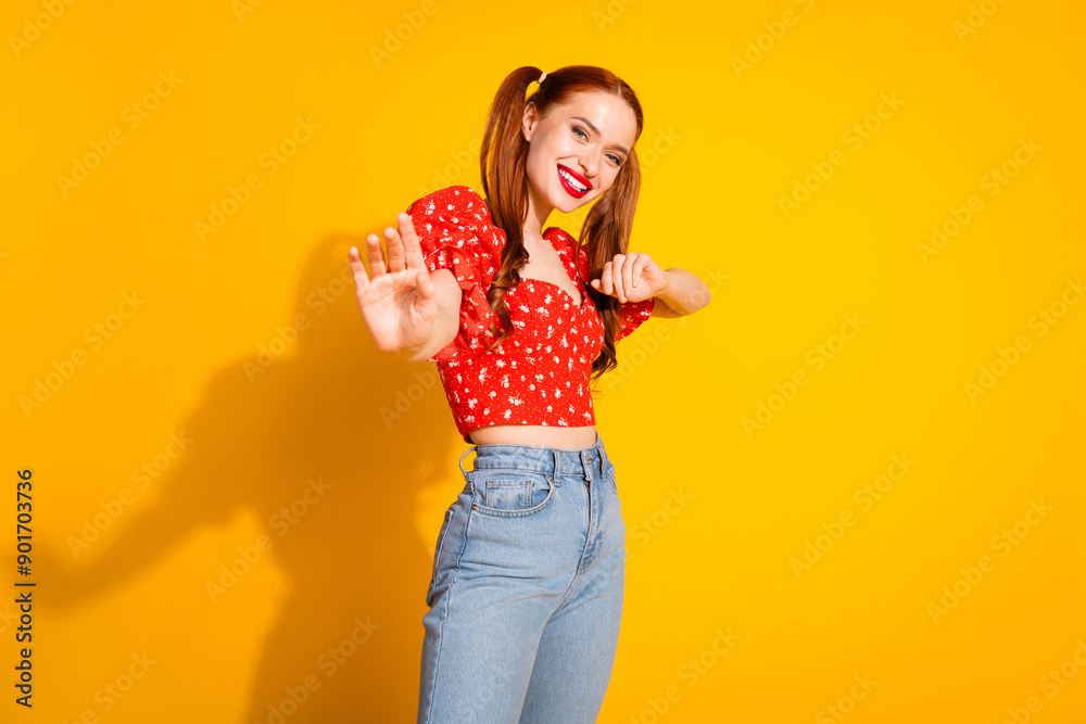 Photo portrait of young red hair funky positive girl wearing blouse and jeans dancing invite you party isolated on yellow color background Photo portrait of young red hair funky positive girl wearing blouse and jeans dancing invite you party isolated on yellow color background