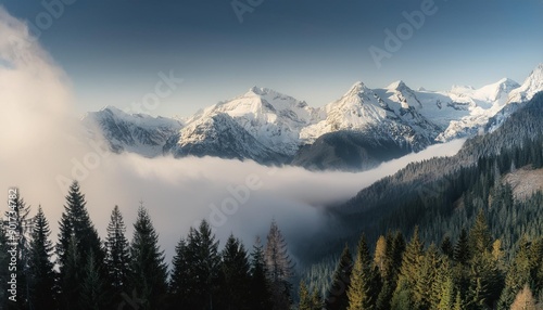 Majestic mountain range with snow-capped peaks and trees, enveloped in a thick mist.