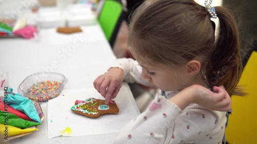 A Curious Child is Enthusiastically Decorating a Gingerbread Cookie with Colorful Sprinkles