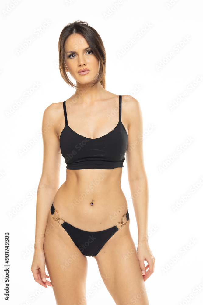 Young brunette woman in bikini swimsuit posing on a white studio background. Front view Young brunette woman in bikini swimsuit posing on a white studio background. Front view
