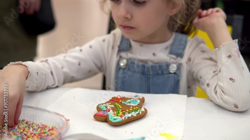 A child joyfully decorating a Christmas gingerbread cookie with colorful icing and sprinkles