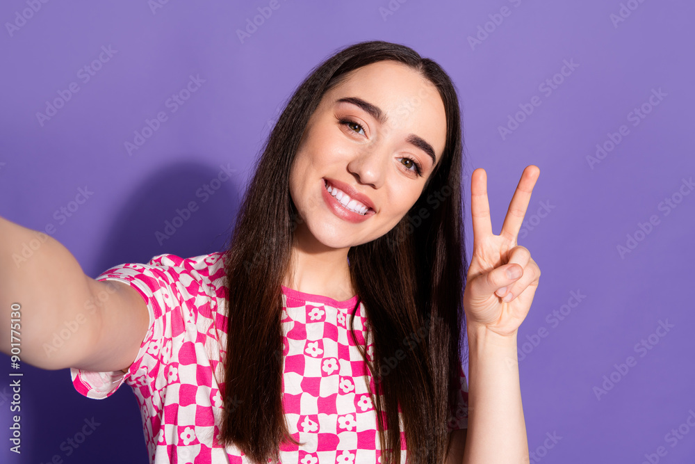 Portrait of nice young woman make selfie show v-sign wear checkered t-shirt isolated on violet color background Portrait of nice young woman make selfie show v-sign wear checkered t-shirt isolated on violet color background