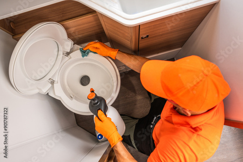 Professional Cleaner Sanitizing Toilet in Modern Bathroom During Daytime