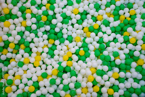 Top view of Beautiful colorful plastic balls in the playground background, Texture of multi colored balls of green, yellow and white. Swimming pool with colored Balls.
