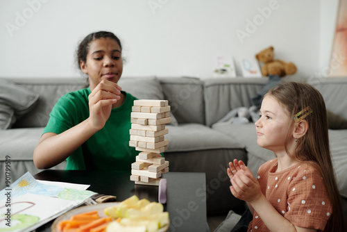 Bilde på lerret Side view of cute little child sitting in front of table and looking at wooden b