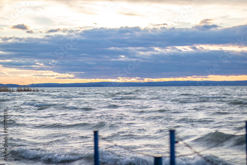 Water landscape taken from the shore of a calm lake. View over the reflecting water to the horizon in the sunset. a jetty or pier at Siofok harbor, Balaton, Hungary photo