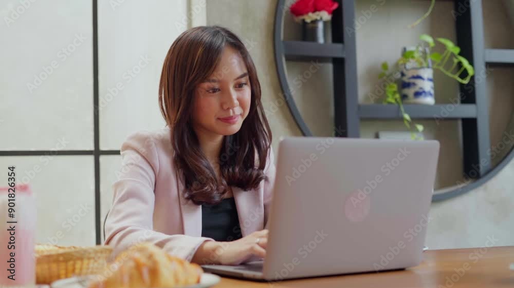 Young professional woman using her phone and laptop in a café, creating a productive and modern work environment. Drinks and snacks are on the table, highlighting a relaxed yet focused atmosphere Young professional woman using her phone and laptop in a café, creating a productive and modern work environment. Drinks and snacks are on the table, highlighting a relaxed yet focused atmosphere