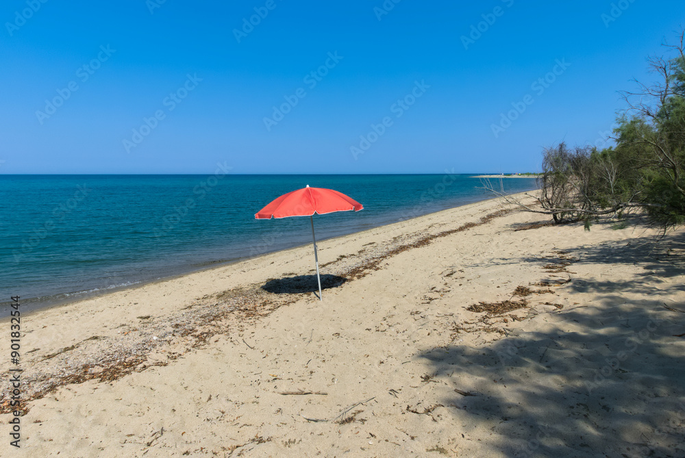 beautiful beach in Ionian Calabria, with lonely red sun umbrella beautiful beach in Ionian Calabria, with lonely red sun umbrella