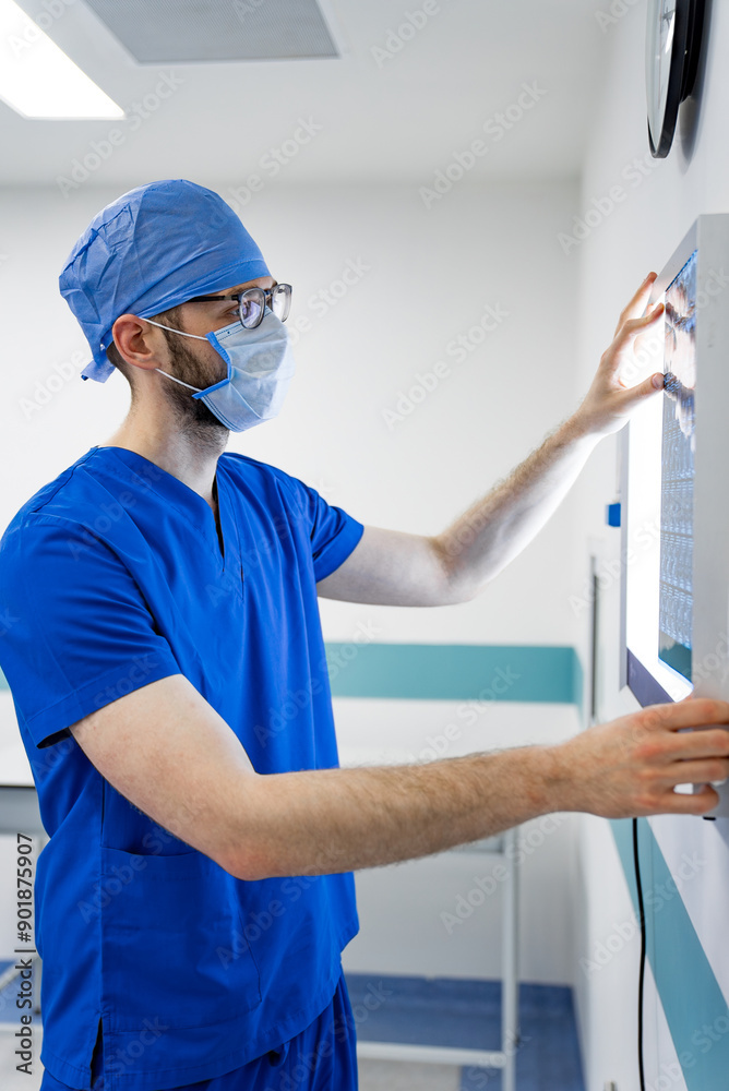 Surgeon Examining X-ray in Hospital. A surgeon in scrubs examines an x-ray in a hospital. Surgeon Examining X-ray in Hospital. A surgeon in scrubs examines an x-ray in a hospital.