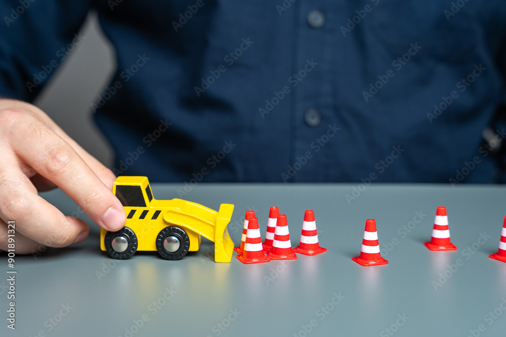 A man removes traffic cones with a bulldozer. The concept of lifting restrictions and prohibitions. Revocation of sanctions and termination of embargo. Termination of seizure and freezing of funds. A man removes traffic cones with a bulldozer. The concept of lifting restrictions and prohibitions. Revocation of sanctions and termination of embargo. Termination of seizure and freezing of funds.