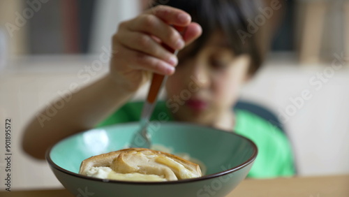 Young boy playfully eating a bowl of pasta, making funny faces and acting goofy, capturing the joy and silliness of childhood during mealtime