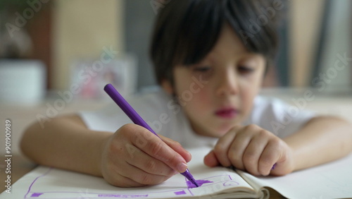 Young child intently drawing with a purple marker, focus on the face and hand, creating artwork, close-up of artistic activity in a home setting, childhood creativity and concentration