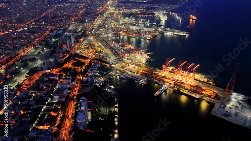A drone flies over a night illuminated seaport, capturing vibrant activity below. night seaport is bustling with movement, highlighting the operations. Night seaport footage shows detailed logistics