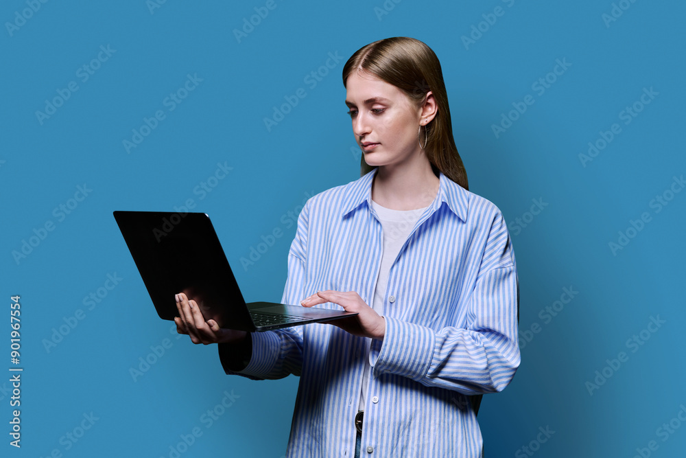 Smiling teenage girl with laptop on blue studio background Smiling teenage girl with laptop on blue studio background